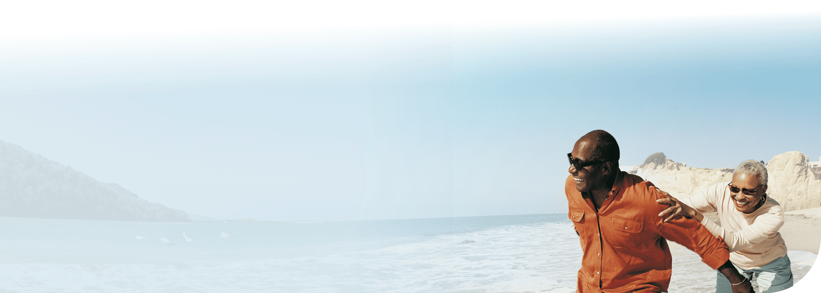 Image of a couple chasing each other with the beach in the background