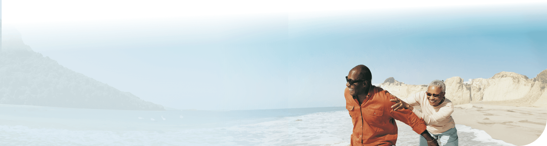 Image of a couple chasing each other with the beach in the background
